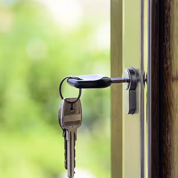 Keys hanging in a door lock with a blurred green background.